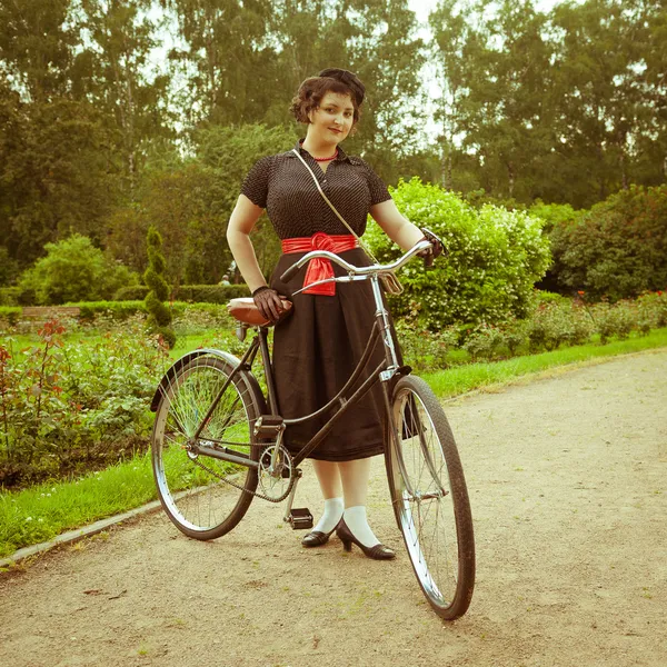 Young woman in dress posing with retro bicycle in the park. — Stock Photo, Image