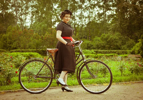 Jovem em vestido posando com bicicleta retro no parque . — Fotografia de Stock