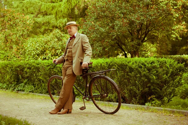 Mature man posing with retro bicycle in the park — Stock Photo, Image