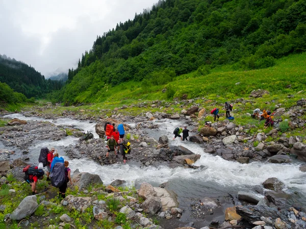 Gruppo escursionisti attraversare il fiume di montagna — Foto Stock