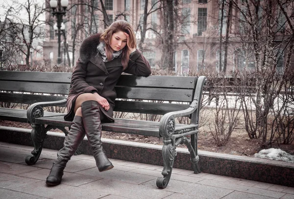 Грустная девушка сидит на скамейке — стоковое фото