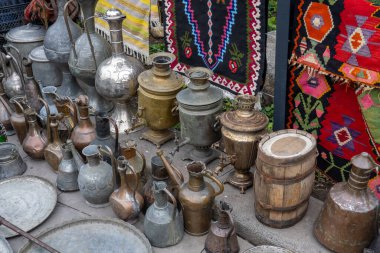 Bit pazarında çeşitli bakır kaplar ve halılar.