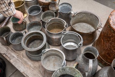 Bit pazarında çeşitli bakır kaplar ve halılar.