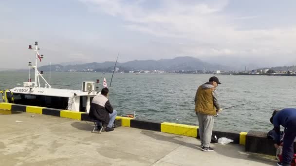 Hombres sentados cerca de barcos en puerto — Vídeo de stock