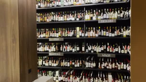 Estantes con botellas en la tienda de vinos — Vídeo de stock