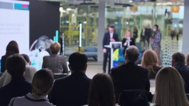İnsanlar iş konferansı sırasında modern salonda toplanıyorlar.