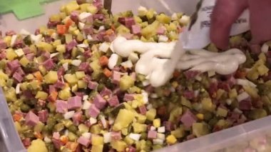 Kırpılmış insan Olivier salatasına mayonez ekliyor.