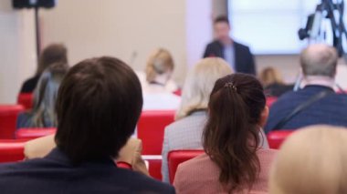 Konuşma sırasında kameranın yanında oturan iş semineri katılımcıları