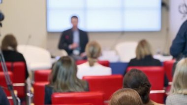 Konuşma sırasında kameranın yanında oturan iş semineri katılımcıları