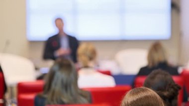 Konuşma sırasında kameranın yanında oturan iş semineri katılımcıları