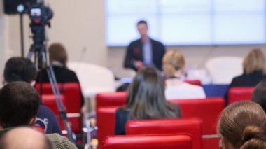 Konuşma sırasında kameranın yanında oturan iş semineri katılımcıları