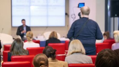 Konuşma sırasında kameranın yanında oturan iş semineri katılımcıları