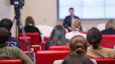 Konuşma sırasında kameranın yanında oturan iş semineri katılımcıları