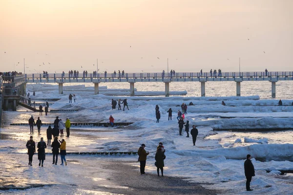 People on frozen embankment at sunset — Stockfoto