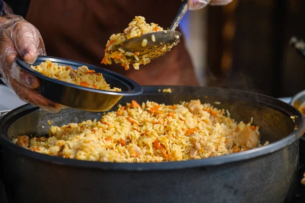 Crop cook serving delicious pilaf 로열티 프리 스톡 이미지