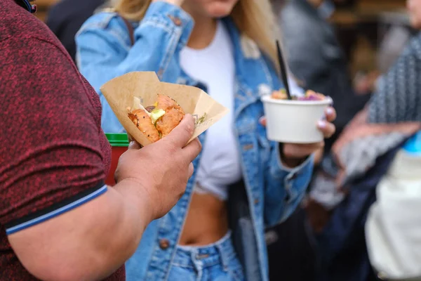 Crop man eating burger in crowd Stock Kép