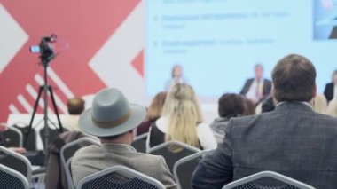 Konuşma sırasında kameranın yanında oturan iş semineri katılımcıları