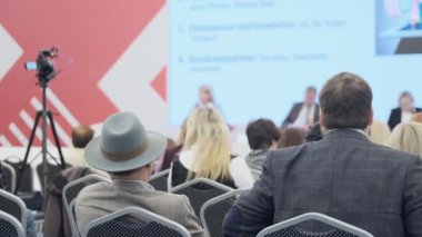 Konuşma sırasında kameranın yanında oturan iş semineri katılımcıları