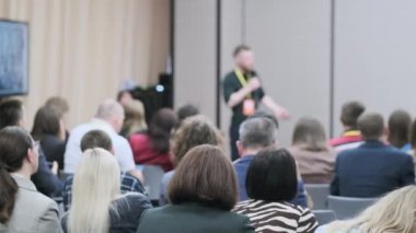 İş konferansına katılan kadın ve erkeklerin oturup hoparlörleri dinlemesi