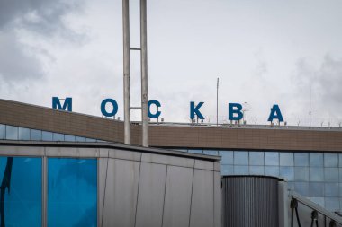 Moskova - 12 Mayıs 2022: Domodedovo Havaalanı 'nın dışı ve çatıda gündüz vakti bulutlu gri gökyüzüne karşı Moskova yazıtları bulunuyor