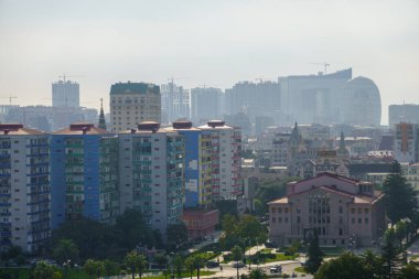 Sabahleyin Batumi, Georgia 'nın yerleşim bölgesinde bulutlu gündoğumu gökyüzüne karşı güneşli bahçe ve apartman manzarası.