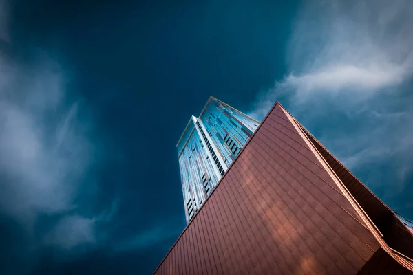 都市の嵐の日に暗い曇りの空に対して位置する近代的な高層ビルの下から ストック画像