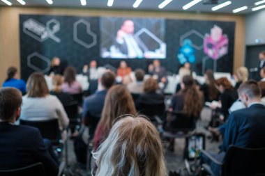 Kalabalık salonda oturan ve konferans sırasında çevrimiçi uzaktan konuşmacının sunumunu dinleyen bir grup iş adamının arka planı