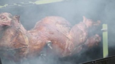 Üniformalı tanınmayan bir aşçı ve eldivenli yüksek açılı park restoranında ızgara tüttürürken dönen et kesiyor.