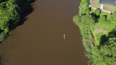 Yukarıdan, güneşli bir günde güneşli bir günde sakin bir nehirde kanoya binen turistlerin drone görüntüsü.