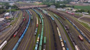 Şehrin banliyölerinde renkli trenlerle modern köprüden geçen çeşitli arabaların insansız hava aracı görüntüsü