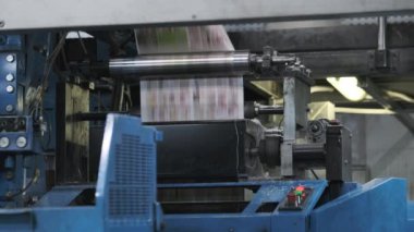 Matbaada çalışırken endüstriyel makinelerden geçen çok renkli kitapçıklar.