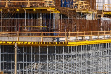 Güneşli bir günde inşaat alanında metal iskeleti olan tamamlanmamış modern bir bina.