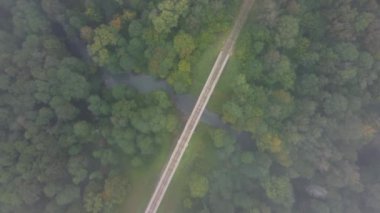 Yukarıdan drone görüntüsü ile köprüyü ve nehri geçerken sisli ormanlık alandaki yeşil ağaçların arasından