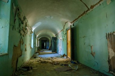 Terk edilmiş binanın içinde yıpranmış duvarlarla kaplı uzun koridorun içi.