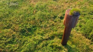 Yukardan bakıldığında, yaz günü yeşil çayırlarda bulunan merdiven ve çimlerle aşınmış su tankı sızıntısı görülüyor.