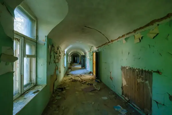 Terk edilmiş binanın içinde yıpranmış duvarlarla kaplı uzun koridorun içi.