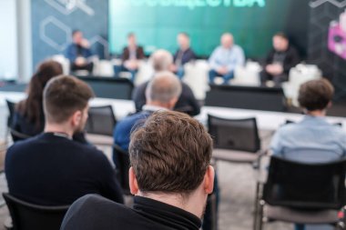 Çağdaş konferans salonundaki iş seminerinde konuşmacıları dinlerken resmi kıyafetli tanınmayan erkek ve kadınların arka planı