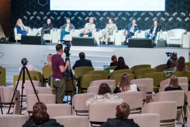 Modern konferans salonundaki seminer sırasında profesyonel konuşmacılar tarafından yapılan sunumları dinleyen bir grup isimsiz erkek ve kadın iş adamının arka planı.
