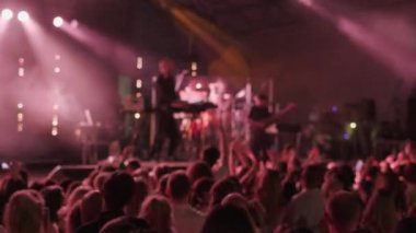 Kalabalık kırmızı neon ışığın altında dans ediyor. Hafta sonu müzik gösterisi sırasında bando şarkıları söylüyor.