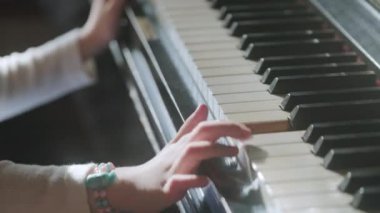 Müzik okulunda ders sırasında güneş ışığında piyano çalmayı öğrenen isimsiz bir kızdan.