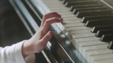 Müzik okulunda ders sırasında güneş ışığında piyano çalmayı öğrenen isimsiz bir kızdan.