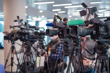 Modern bina içindeki kamu etkinliği sırasında kameraların arkasında duran ve televizyon röportajını kaydeden isimsiz adamların yumuşak odağı