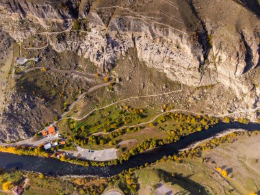 Gürcistan 'ın kırsal kesimlerinde güneşli bir günde sert kayalara oyulmuş Vardzia mağara manastırının insansız hava görüntüsü.