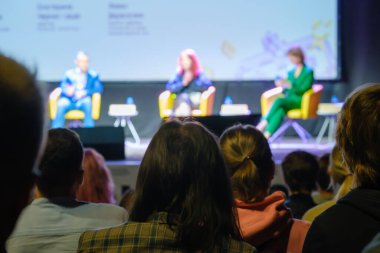 Sahnenin bulanık arka planında karanlık oditoryumda otururken hoparlörleri dinleyen tanınamayan insanlar