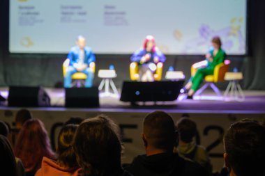 Sahnenin bulanık arka planında karanlık oditoryumda otururken hoparlörleri dinleyen tanınamayan insanlar