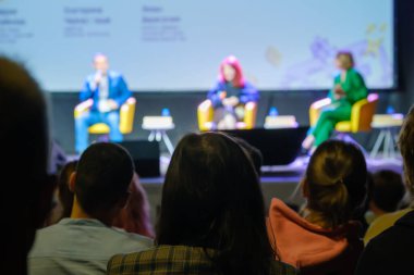 Sahnenin bulanık arka planında karanlık oditoryumda otururken hoparlörleri dinleyen tanınamayan insanlar