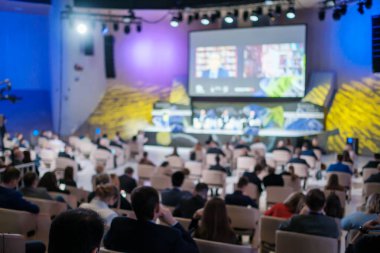 Modern salondaki iş seminerinde sandalyelerde otururken çevrimiçi konuşmacıları dinleyen isimsiz girişimcilerin yumuşak odağı