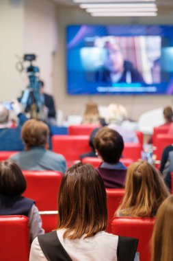 Dar oditoryumdaki iş seminerinde çevrimiçi konuşmacı dinleyen insanlar