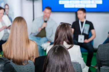 Sandalyelerde oturan ve halk etkinliği sırasında hoparlörleri dinleyen isimsiz kadınların yumuşak odağı.