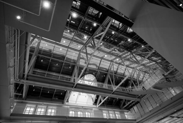 Снизу черно-белый металлический потолок современного здания с окнами и лампами